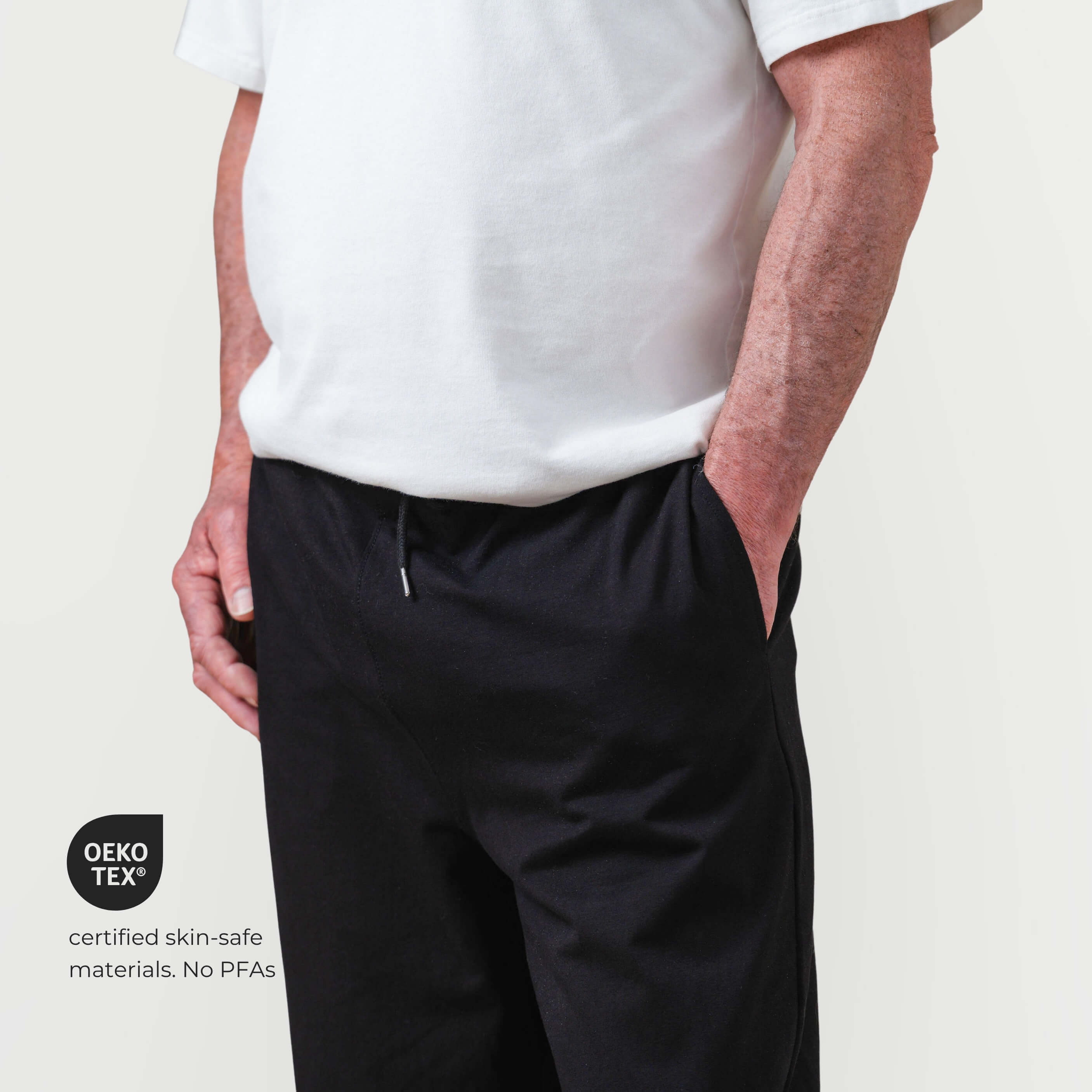 Person wearing black pants and a white shirt on a plain background with GEKO TEX certification logo.