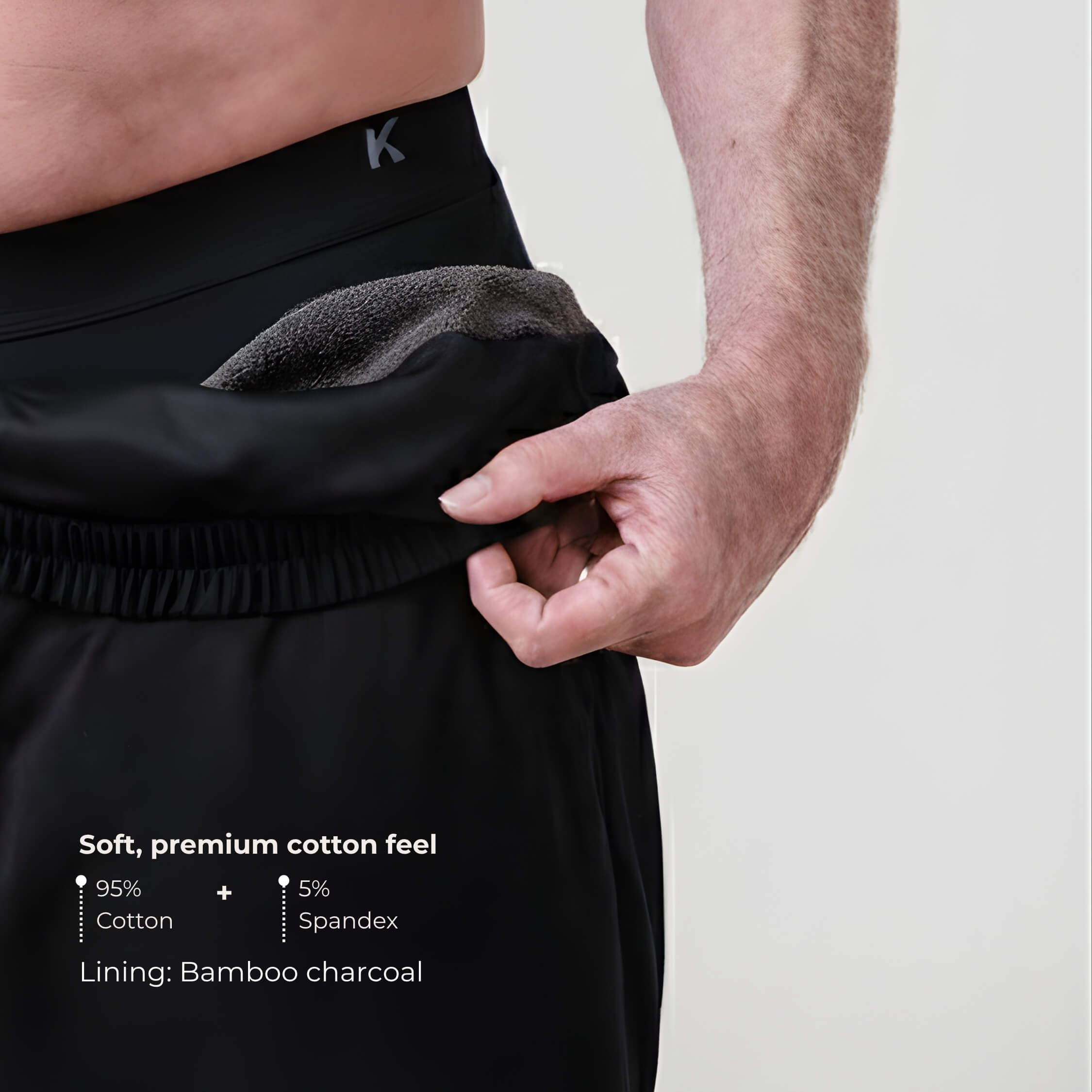 Person wearing black shorts with a close-up of the waistband on a light gray background.