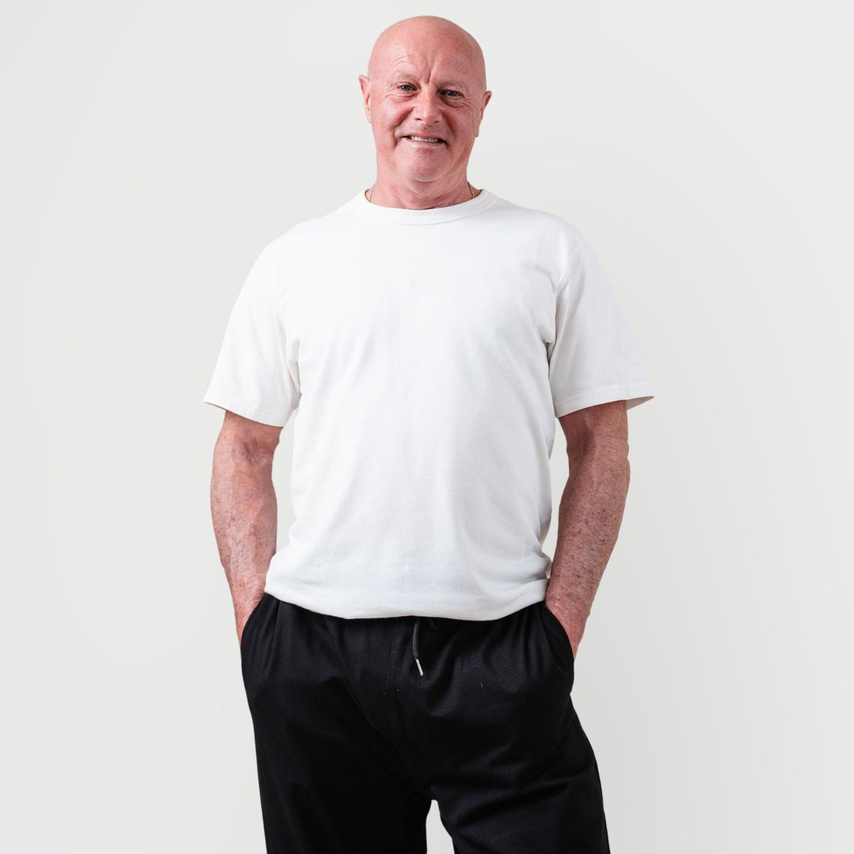 Man wearing a plain white t-shirt and Kovered leakproof black pants against a light gray background